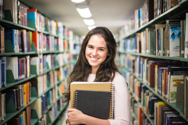 Job als Werkstudent Werkstudent steht mit Heften in der Bibliothek