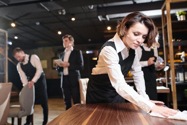 Kellner*in beim Nebenjob. Die Plätze im Restaurant werden gereinigt.