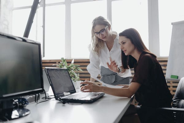 arbeitsformen-dienstplan-software Zwei Kolleginnen besprechen den Dienstplan des kommenden Monat im Büro