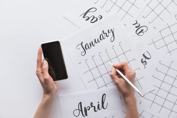 Eine Person hält ein Handy in der Hand und plant den Dienstplan für Januar.