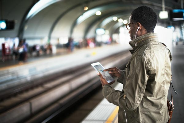 Man wartet am Bahnhof mit Tablet in der Hand