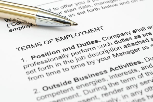 arbeitsrecht-arbeitsvertrag Nahaufnahme eines Kugelschreibers, der auf einem Arbeitsvertrag über der Überschrift „TERMS OF EMPLOYMENT“ liegt.