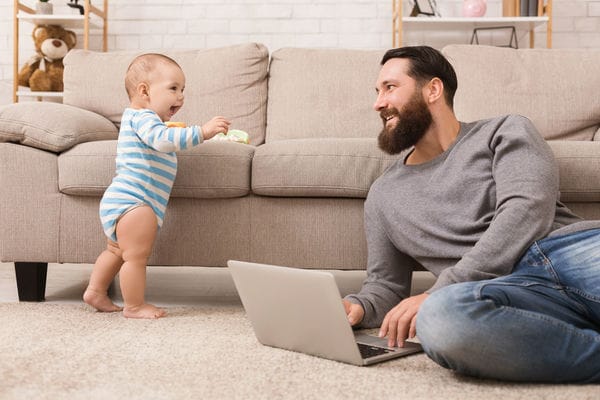Vater mit Sohn im Homeoffice mann mit baby im wohnzimmer