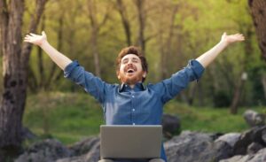 Glücklicher Mann sitzt im Park glücklicher mann mit laptop