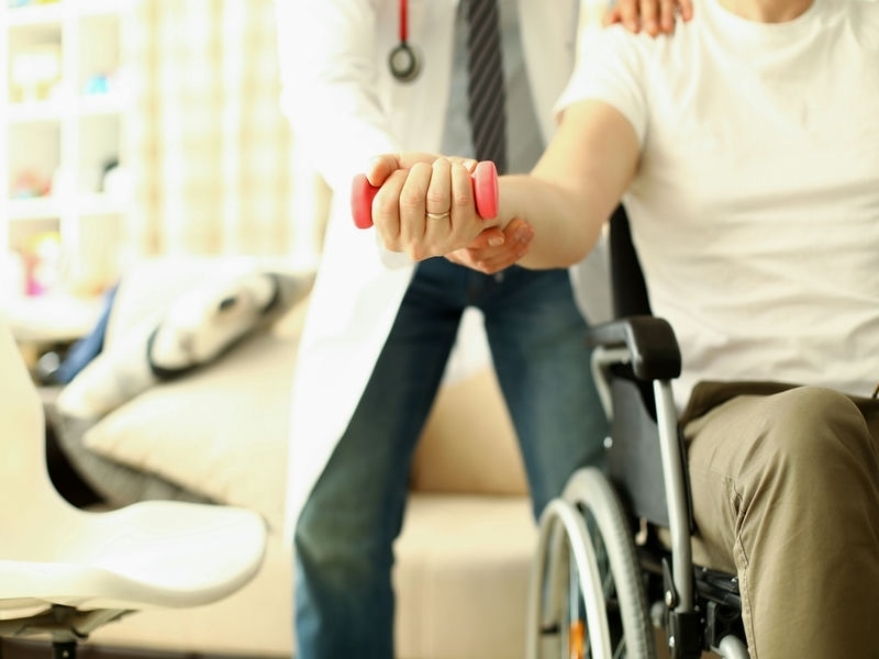 Eine Berufsunfähigkeitsversicherung kann Sicherheit bieten Arzt hilft Hantel zu Rehabilitationskonzept für behinderte Patienten zu heben.