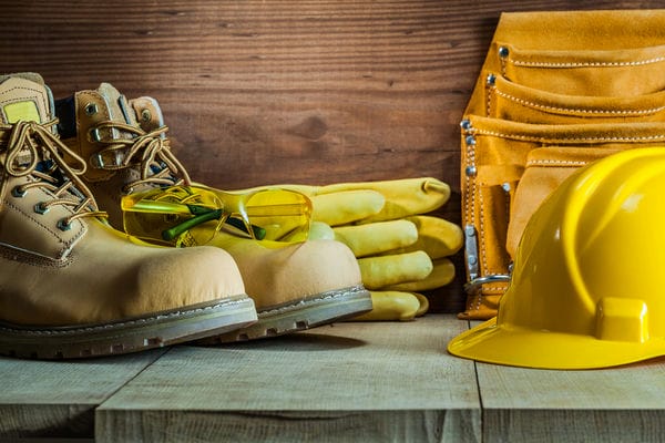 unternehmen-arbeitskleidung-firmendesign ein Tisch mit verschiedener Arbeitskleidung wie Schutzbrille, Helm oder Sicherheitsschuhe