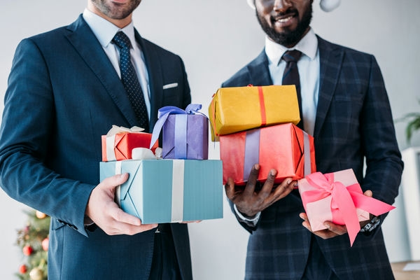verguetung-unternehmen-geschenke-fuer-kunden-mitarbeiter Geschäftsleute halten Geschenke in den Händen