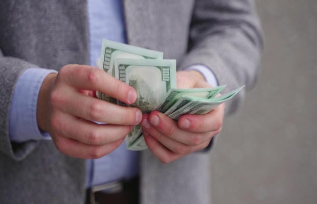 verguetung-einkommen Eine Person in Business-Kleidung zählt Bargeld für das monatliche Einkommen.