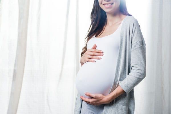 verguetung-mutterschaftsleistungen-einkommenssicherung Schwangere berührt Bauch